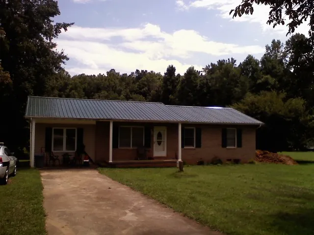 Dark green metal roof on a brick ranch with a covered porch in Lake Orion