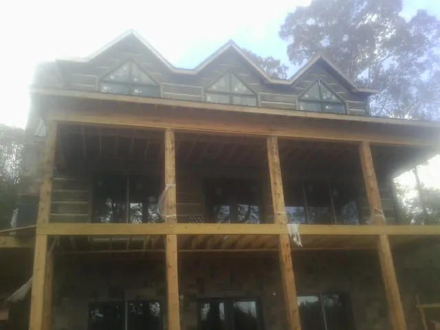 Dormers and porch framing on a large log home under construction — Roof Coating work by our crew in Lake Orion