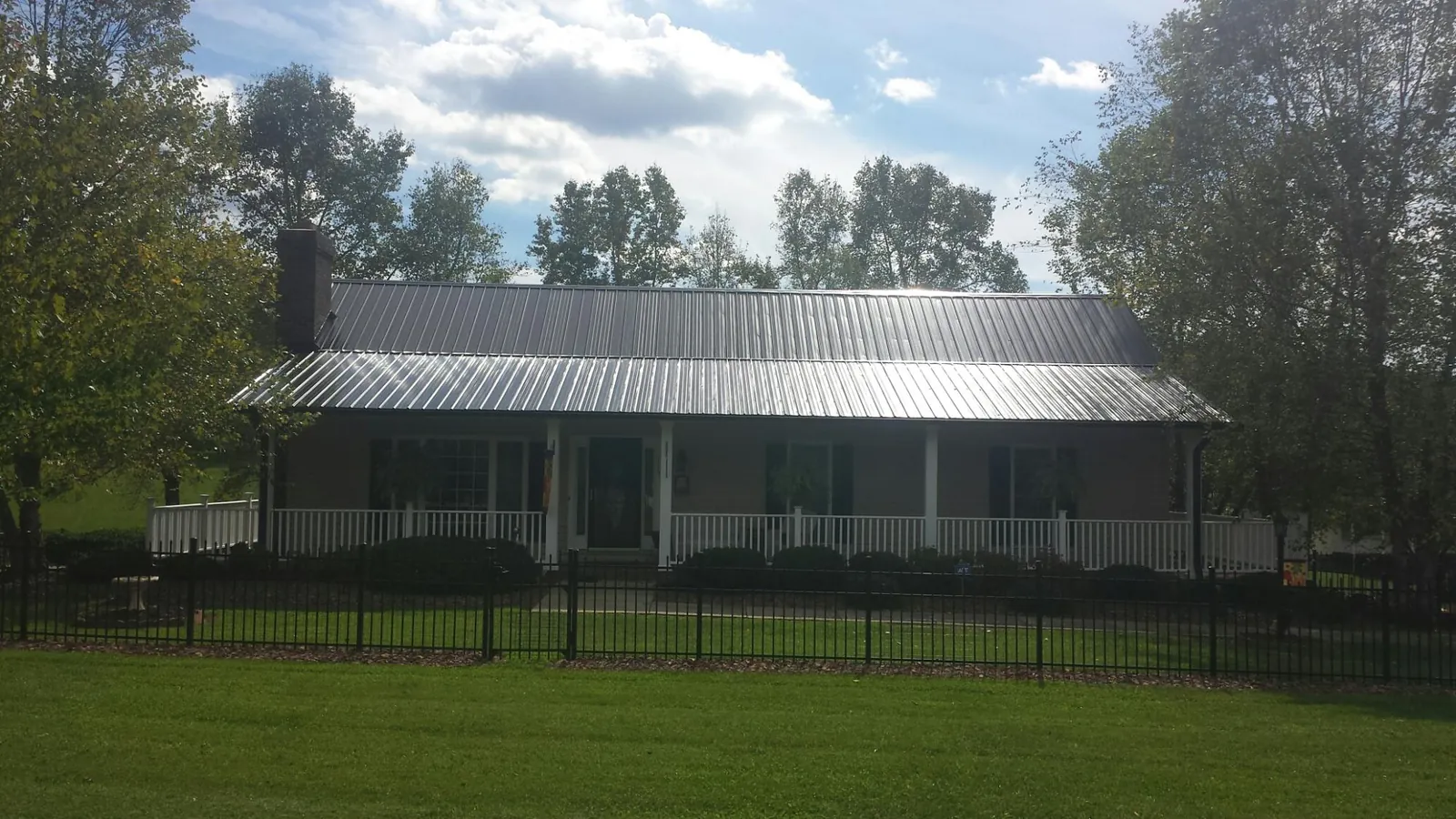 Gray metal roof on a brick ranch with a full width front porch — Gutter Guard Installation work by our crew in Lake Orion