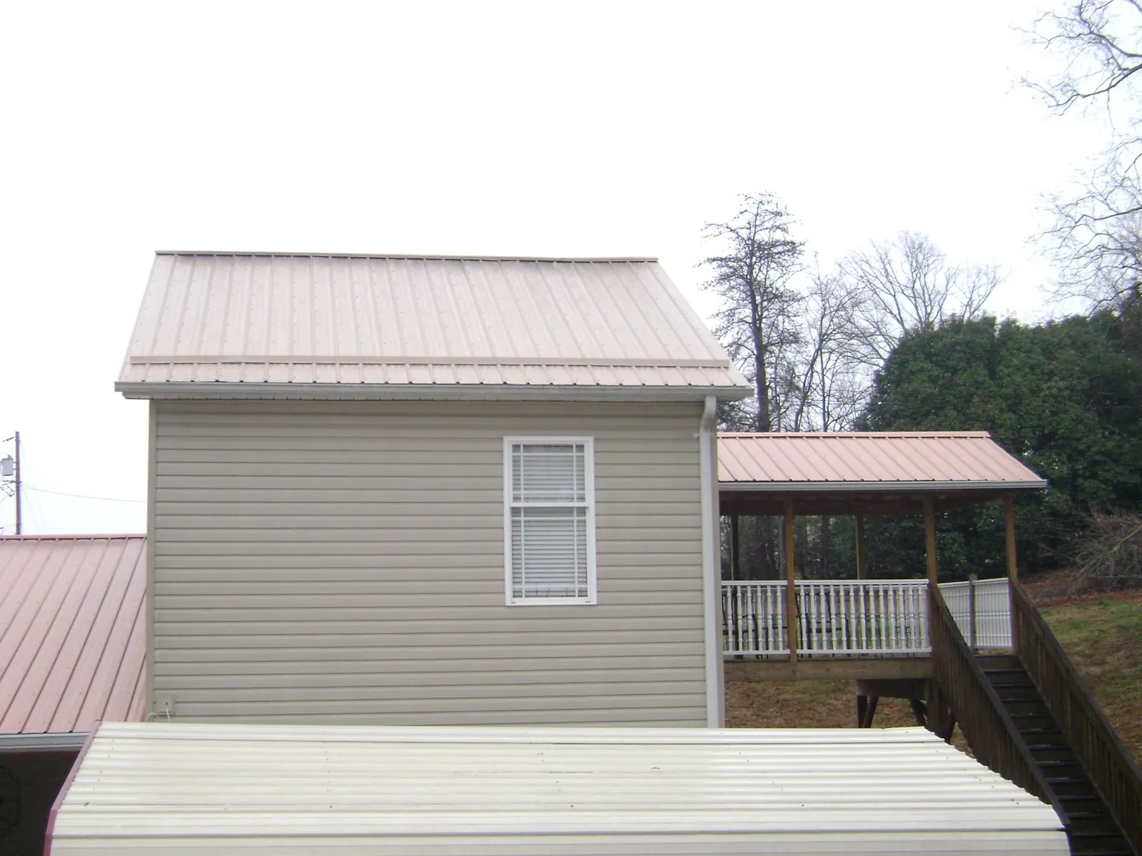 Tan metal roofs on a two story addition and attached porch, from a Roof Replacement job in Lake Orion
