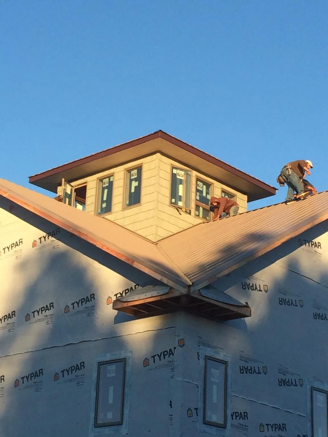 Roofers working around a rooftop cupola on a new metal roof at sunset — Roof Waterproofing in Lake Orion by Roofing Brothers